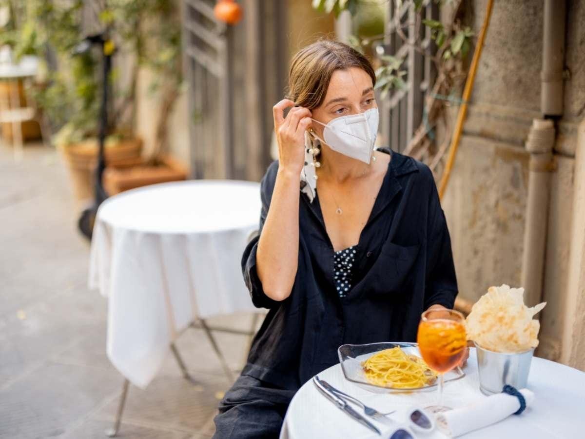 Girl wearing mask sitting  in outdoor restaurant 