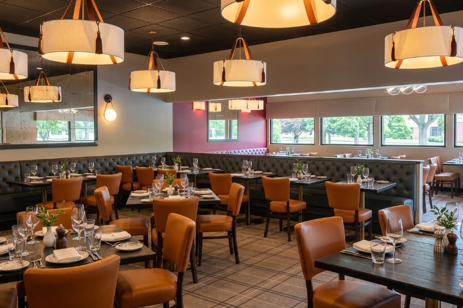 Renovated restaurant dining room at the former New Hope Diner featuring upholstered chairs, tufted booths, black wood tables, brass bases, and warm pendant lighting.