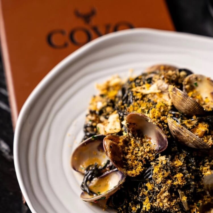 COVO Italian Steakhouse table setting with black stone-look table top and cognac restaurant chairs.