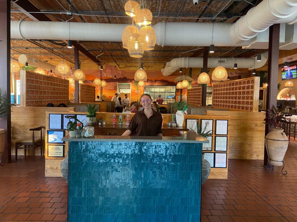 De Nada Birmingham interior with colorful Mexican-inspired desert mural, custom striped restaurant booths, terracotta tile floor, woven pendant lights, exposed ductwork, and decorative breeze-block partitions.