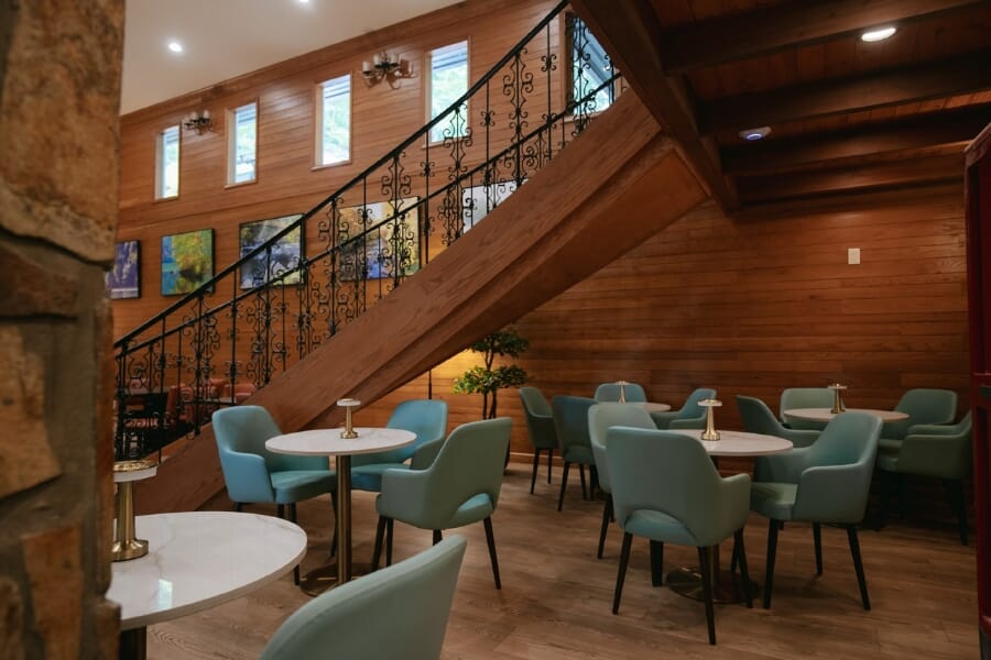 Lake Santeetlah Lodge main dining room with persimmon Bennett chairs, walnut tables, stone columns, and wood walls.