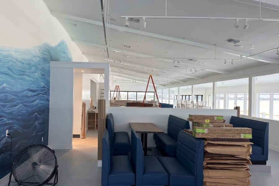 Latitude 26 waterfront booth seating with blue upholstery, wood table tops, and panoramic Charlotte Harbor views.