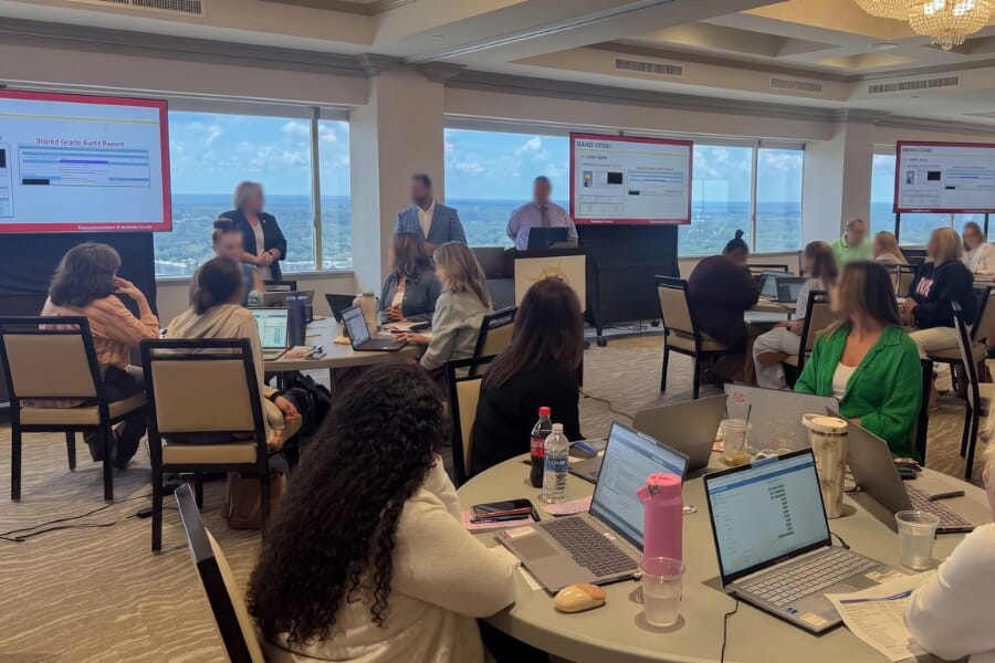 Quick ship hospitality chairs used in a classroom-style professional training session with round tables, laptops, and presentation screens.