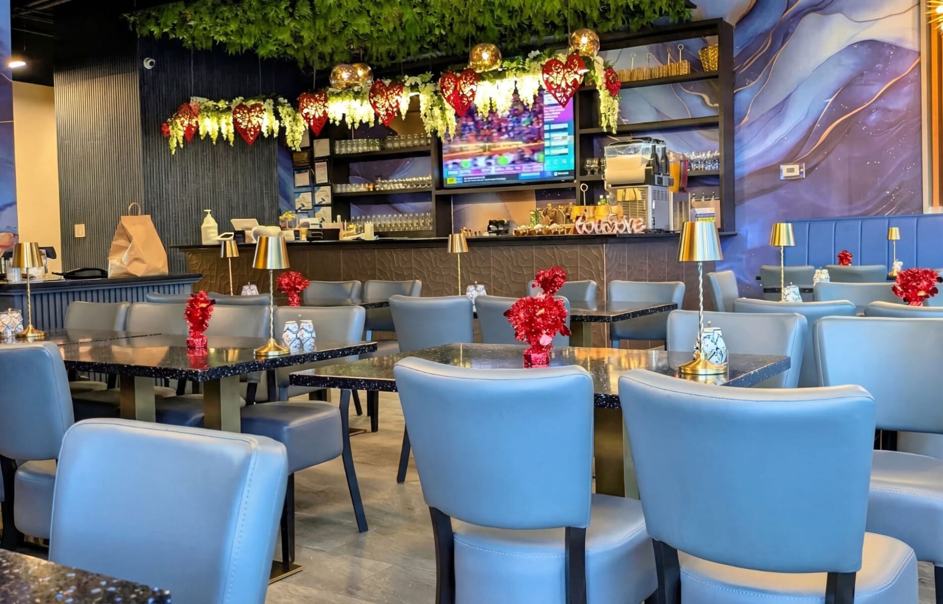 Dining room interior at Blaze on Fire Restaurant and Grill in Hackensack New Jersey featuring powder blue leather chairs, dark granite tables, floral ceiling installation, and abstract wall mural