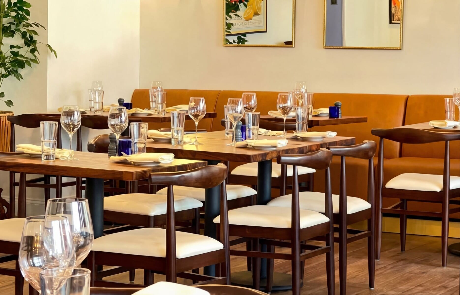 Bright dining room interior at Butter and Brie in Pleasantville New York featuring walnut tables, cream upholstered chairs, and cognac leather banquette seating