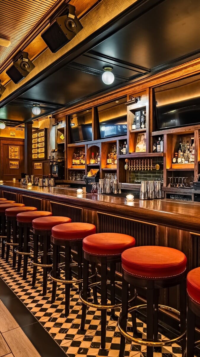 Central Park Tavern bar area with leather stools, brass accents, and a fully stocked back bar in Midtown Manhattan