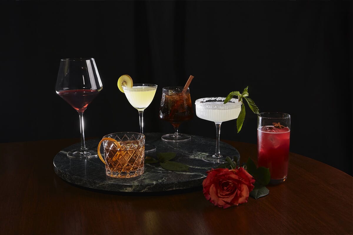 A table adorned with various drinks and a single rose, showcasing a sophisticated atmosphere at Mockingbird in Park Slope.