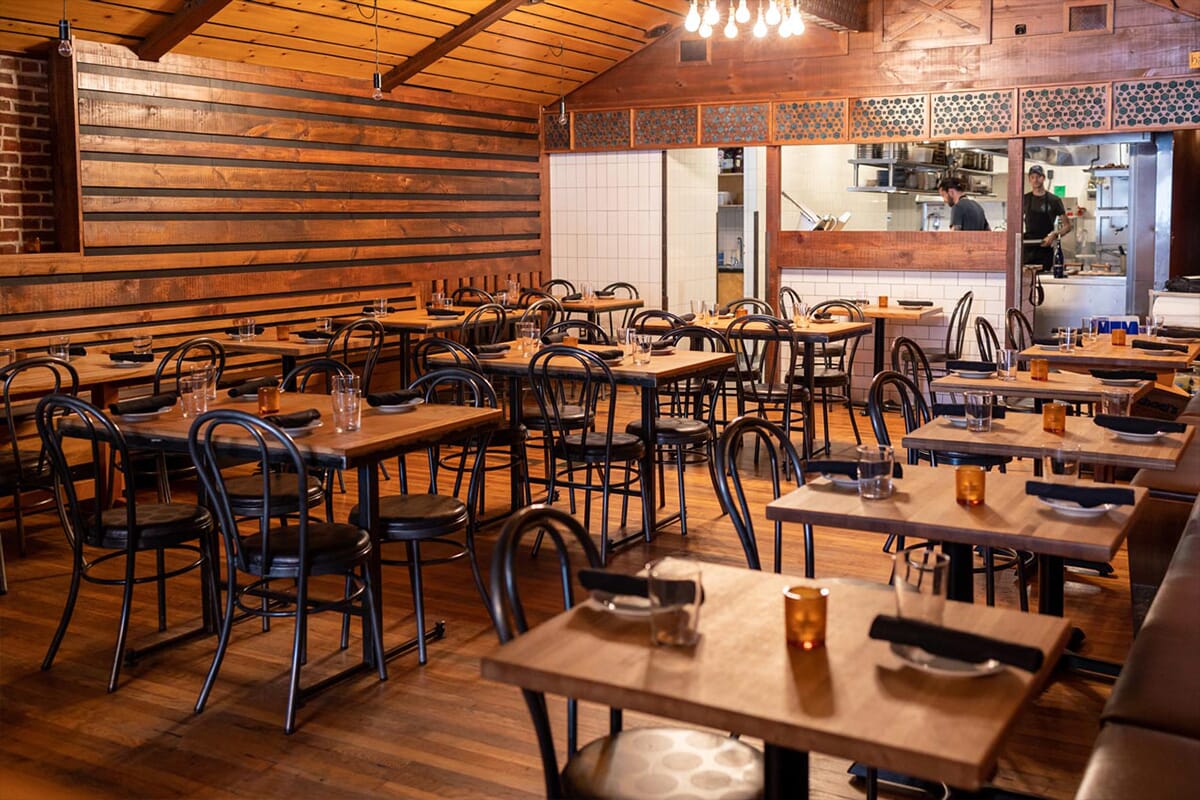 A warm dining space with wooden walls and tables, showcasing a fusion of traditional Spanish cuisine and contemporary design.