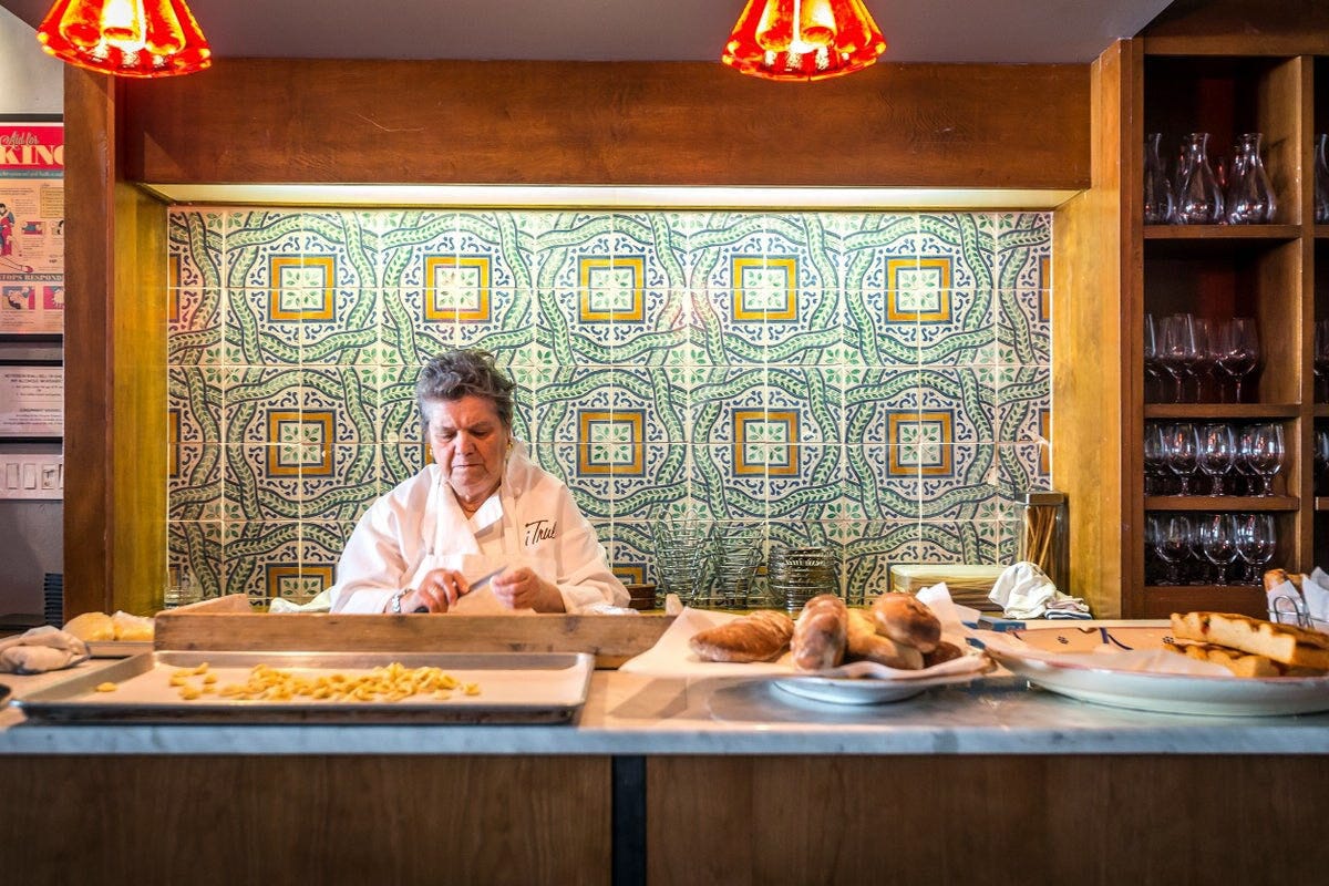 Nonna Dora diligently crafts fresh pasta in a vibrant restaurant, highlighting the essence of traditional Italian culinary artistry