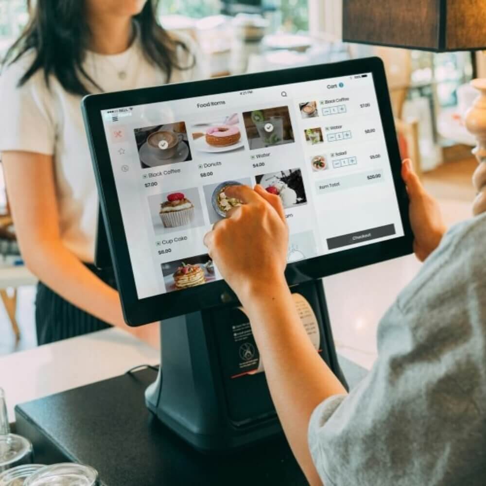 Restaurant employee using a POS touchscreen to enter food orders at a cafe counter