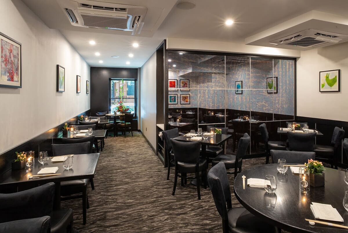 The main dining space at Sushi Nakazawa, with tables and chairs arranged for guests to indulge in a masterful omakase meal.