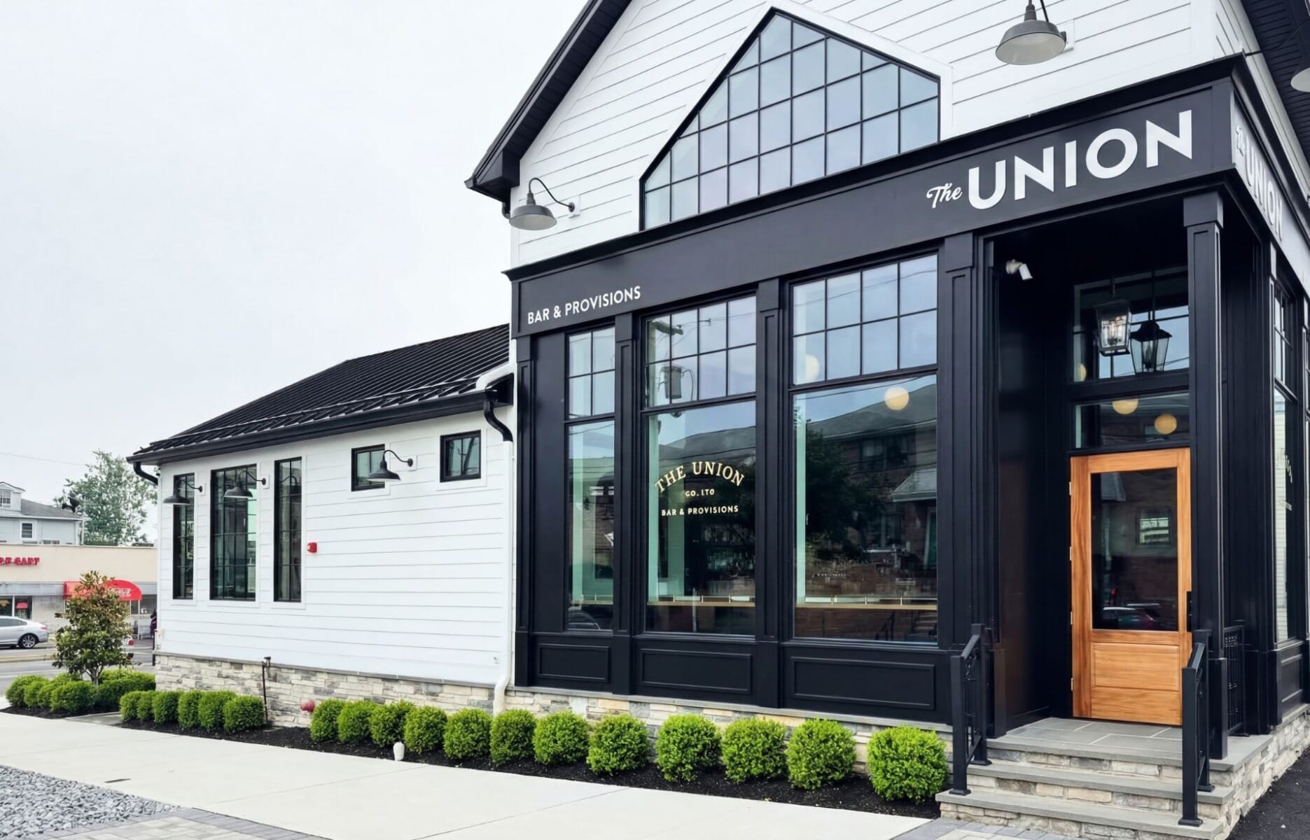 Exterior of The Union Bar and Provisions in East Rutherford New Jersey featuring modern farmhouse design with white shiplap siding, black window frames, and gabled greenhouse window