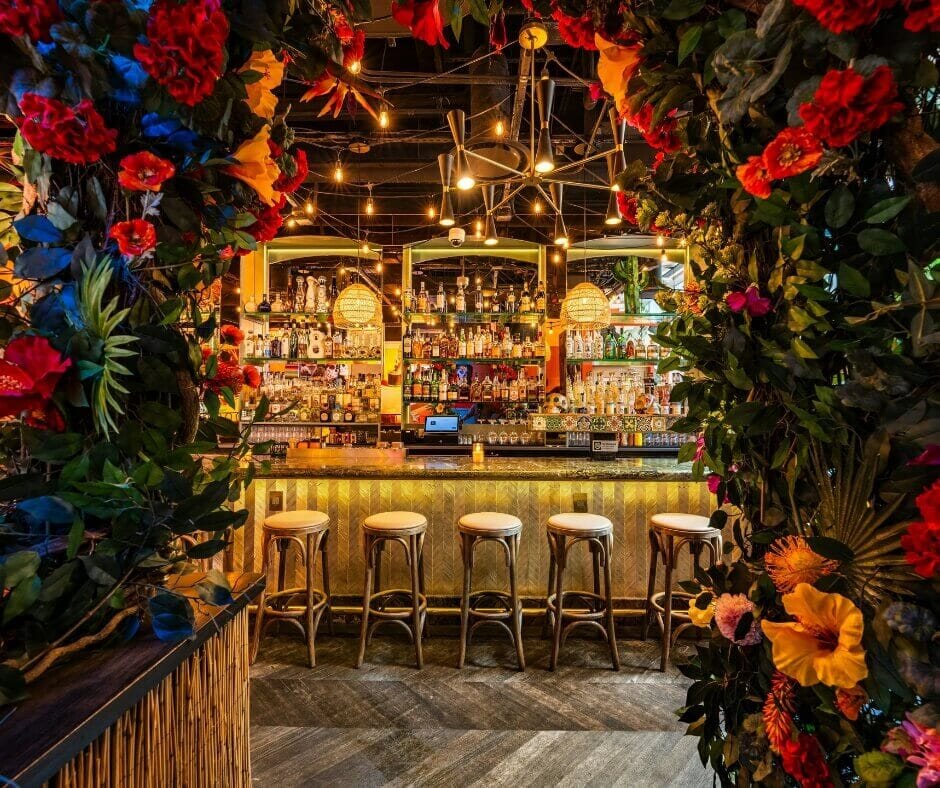Floral archway leading to the interior bar at Vida Verde Tequila Bar in Midtown NYC with colorful décor and tropical lighting