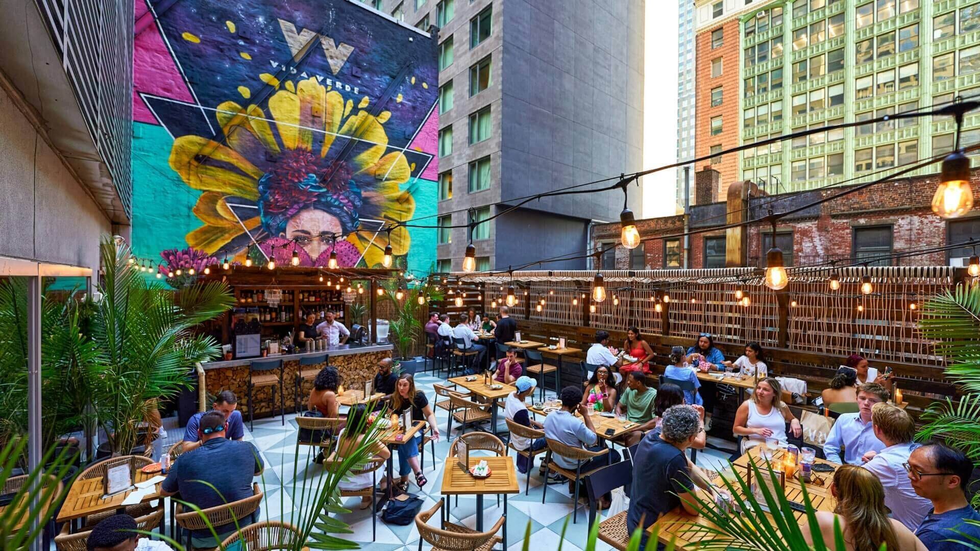 Rooftop dining area at Vida Verde Tequila Bar in Midtown Manhattan with colorful mural and vibrant outdoor seating