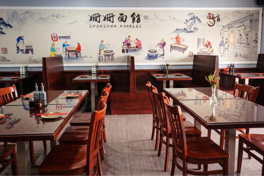 Shan Shan Noodles restaurant in Parsippany New Jersey featuring custom mahogany solid wood booths, matching oak dining tables, and brushed stainless steel commercial table bases.