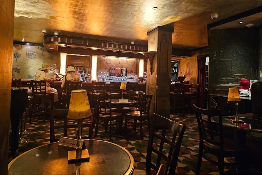 Luxury hospitality seating at Bemelmans Bar inside The Carlyle Hotel featuring dark mahogany lattice-back wood chairs, Tea Rose upholstered seats, and classic New York bar design.