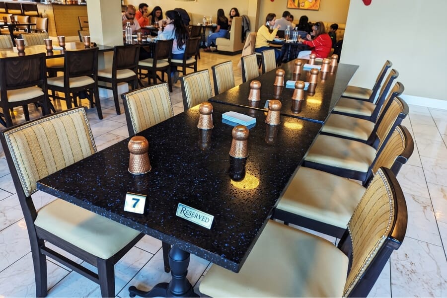 Taste of India restaurant in Destin Florida featuring custom upholstered Madison chairs, walnut wood frames, Blue Galaxy quartz tables, and a modern Indian dining room.
