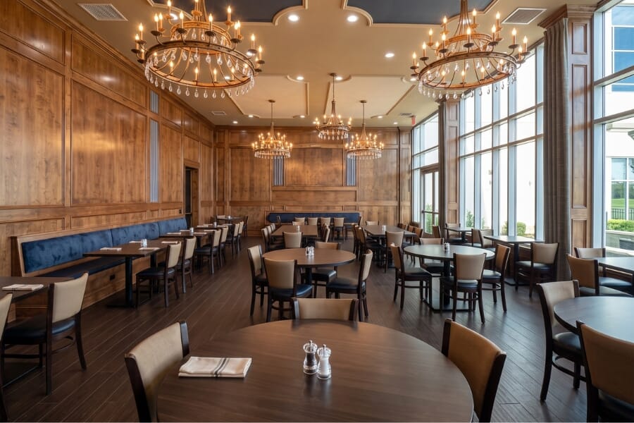St. Joseph by-the-Sea High School dining hall in Staten Island featuring custom upholstered restaurant chairs, walnut solid oak tables, and black commercial table bases.