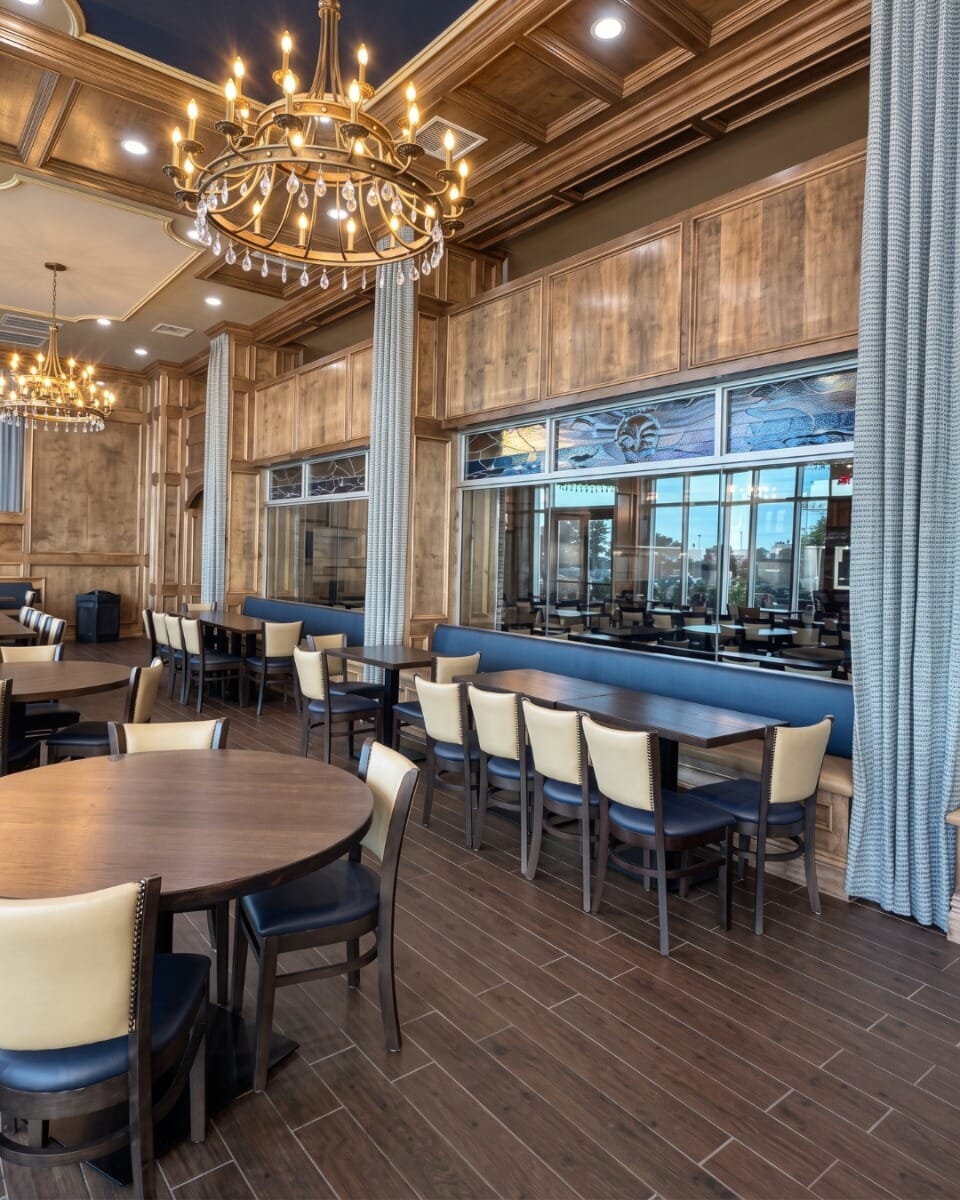 St. Joseph by-the-Sea school dining hall showing walnut solid oak tables in multiple sizes, custom upholstered commercial chairs, and black metal table bases.