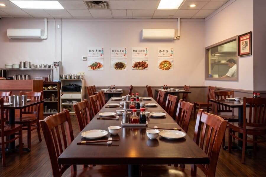 Custom mahogany solid oak restaurant tables paired with solid wood booths and brushed stainless steel commercial bases at Shan Shan Noodles.