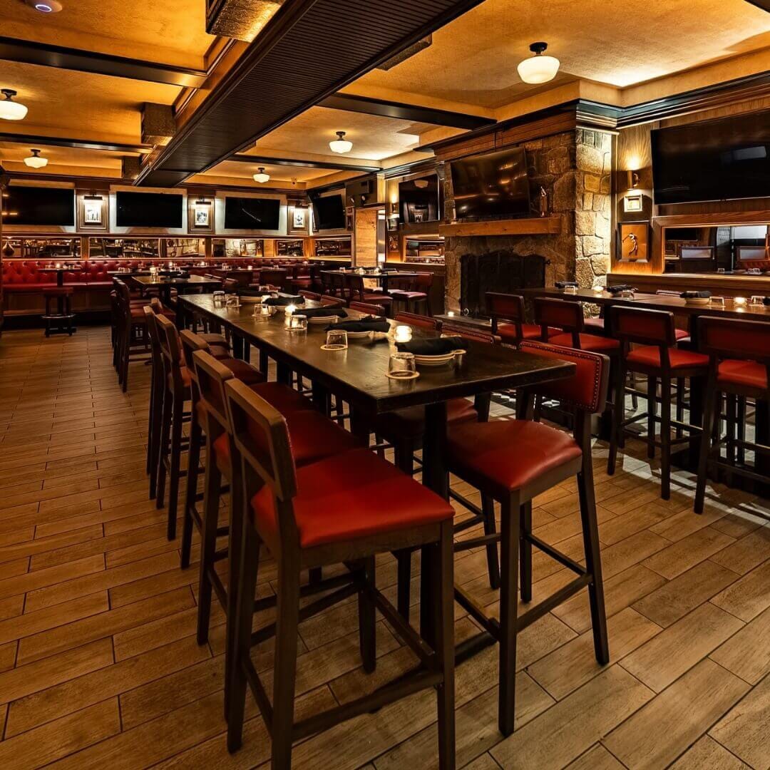 Spacious dining room and bar area at Central Park Tavern NYC with high-top tables, red upholstered seating, and warm tavern lighting for a sports bar vibe.