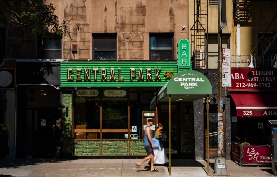 Exterior street view of Central Park Tavern NYC on West 57th Street, showing the green facade, awning, and entrance to the Midtown sports bar.