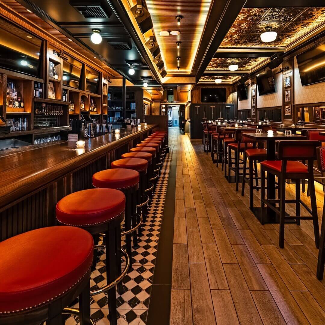 Full interior view of Central Park Tavern in Midtown Manhattan featuring walnut tables, brass bar stools, and black-and-white tile flooring for a modern tavern style.