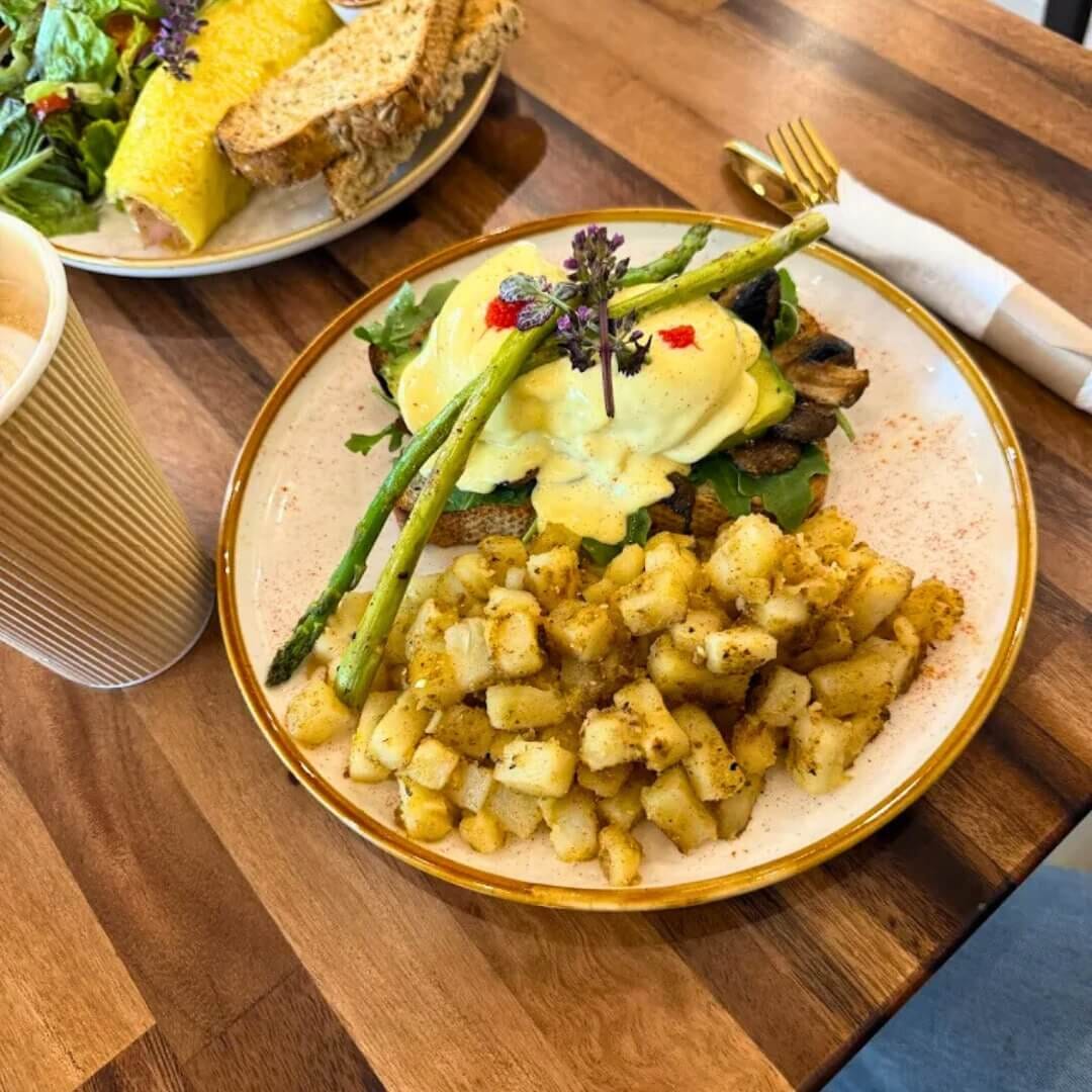 Breakfast plate with potatoes and avocado toast on walnut restaurant table at STL Cafe
