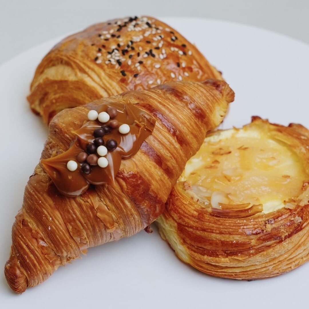 Trio of pastries including croissant and custard tart on white plate at STL Cafe