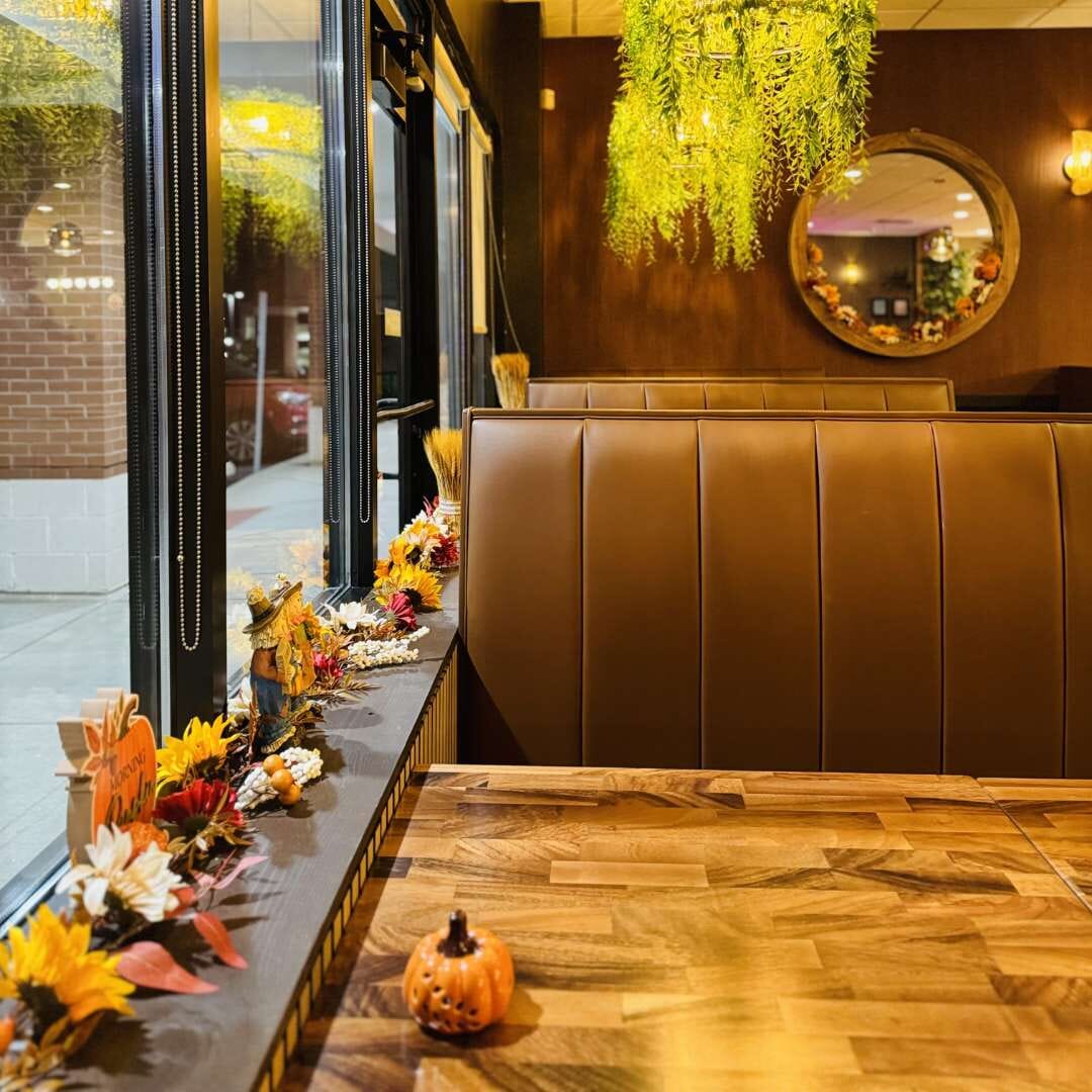 Chestnut channel-back booth at Thai Season Carmel with walnut table, fall decor on windowsill and greenery chandelier.