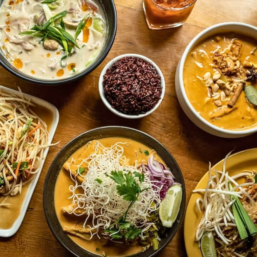 Overhead view of Thai Season spread with tom kha soup, yellow curry, papaya salad and black rice.