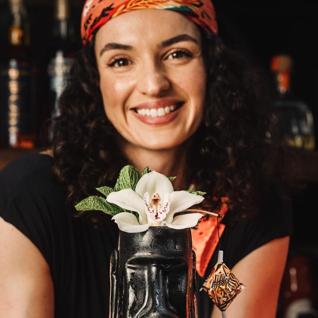 Guest holding tiki-style tequila cocktail garnished with orchid flower at Vida Verde NYC