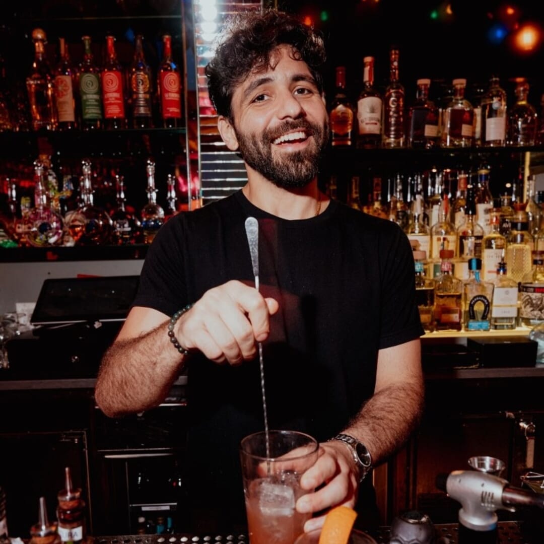 Smiling bartender crafting tequila cocktail at Vida Verde rooftop tequila bar in Midtown Manhattan