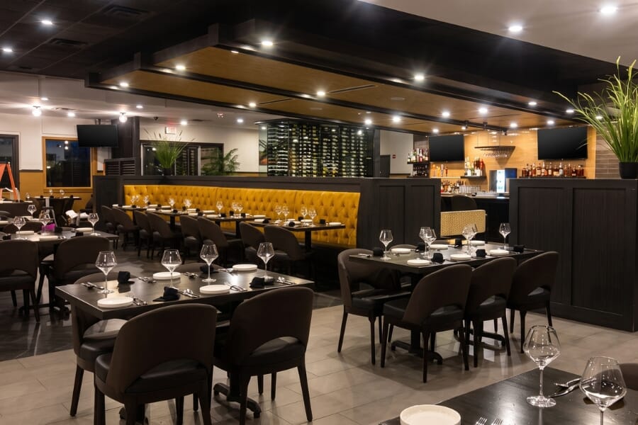 Wine display at Italian Chophouse on Lake Oconee with surrounding dining room, upholstered restaurant seating, and dark commercial furniture.
