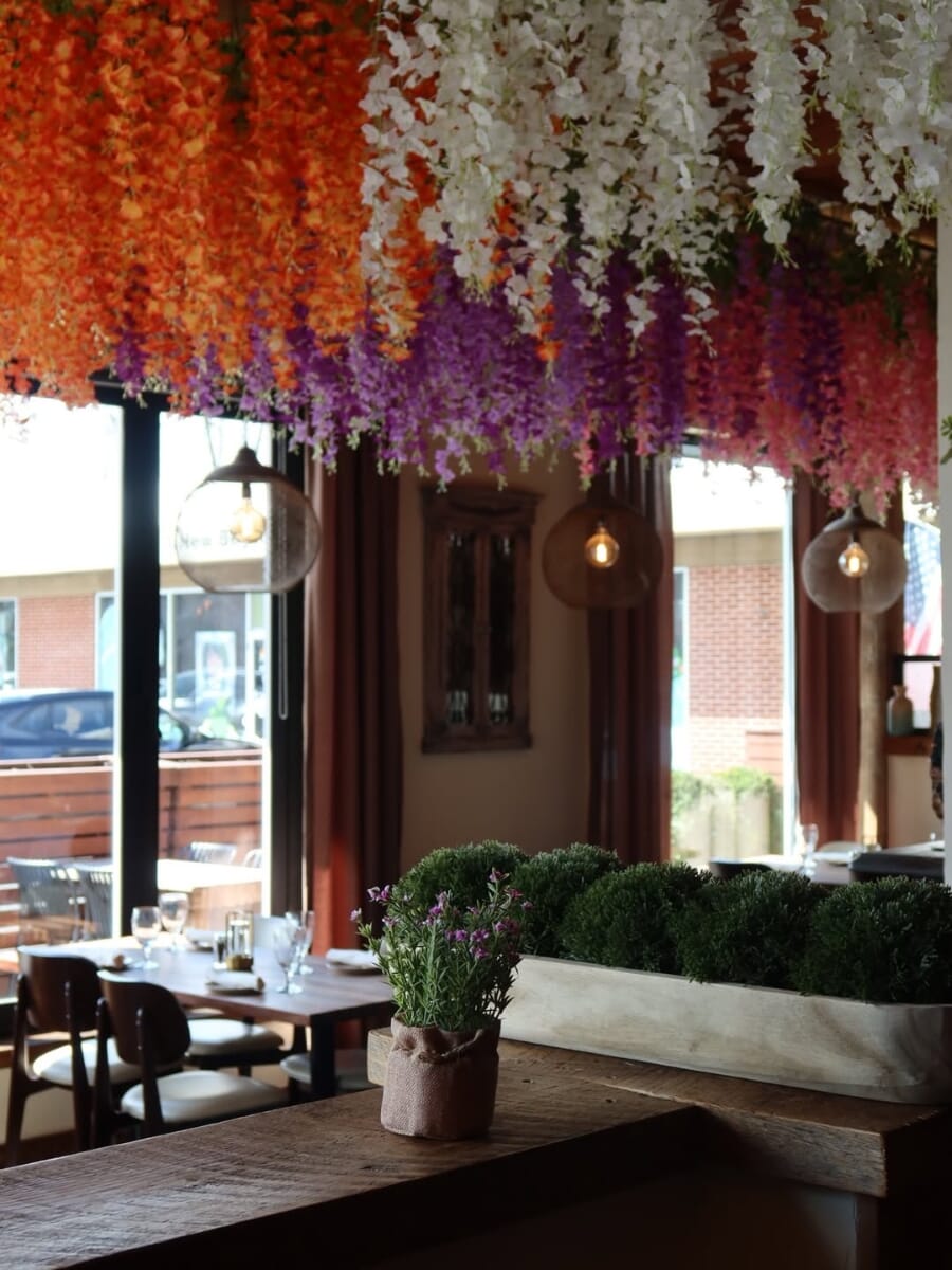 Warm bar and dining atmosphere at Bora Restaurant in Bethel Connecticut featuring wood ceilings, floral décor, pendant lighting, and commercial restaurant seating.