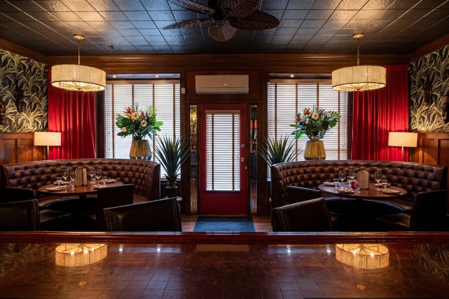 Interior of The Blue Shutters restaurant featuring walnut tables, tufted booths, and wood seating.