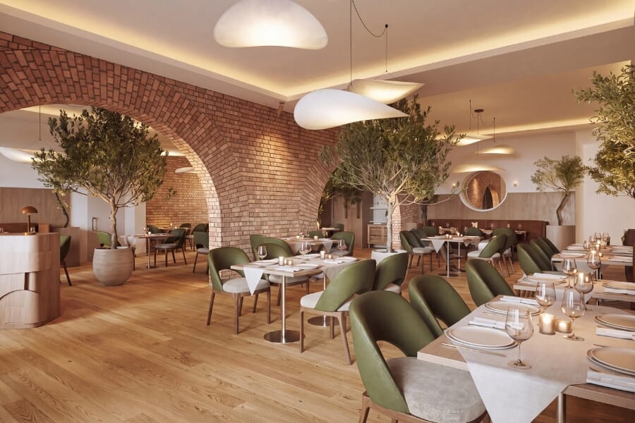 Clementina Italian restaurant in Upper Montclair featuring exposed brick arches, maple restaurant table tops, stainless steel table bases, natural wood restaurant chairs, olive green upholstery, greenery, and warm Mediterranean-inspired interior design.