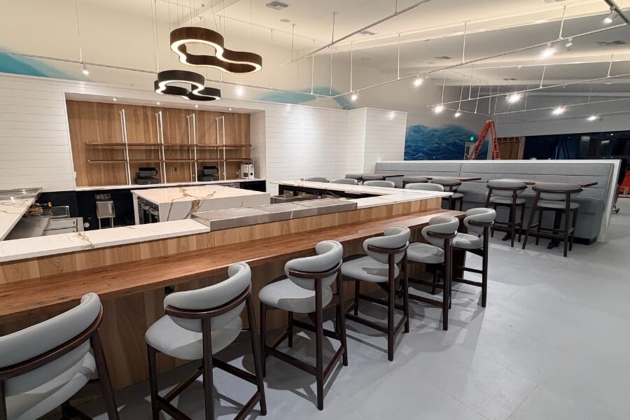 Latitude 26 waterfront dining room at Fishermen's Village featuring blue restaurant booths, warm wood table tops, and Charlotte Harbor views.