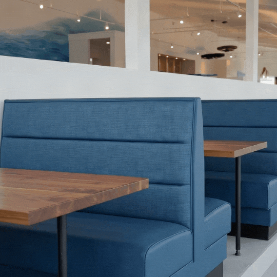 Latitude 26 waterfront booth seating with blue upholstery, wood table tops, and panoramic Charlotte Harbor views.